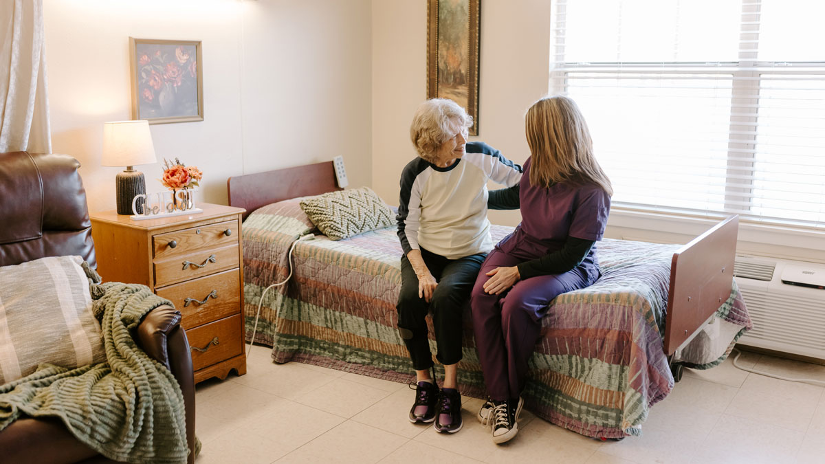 Elder and Staff Member in Patient Room at Courtyard Rehabilitation and Health Center